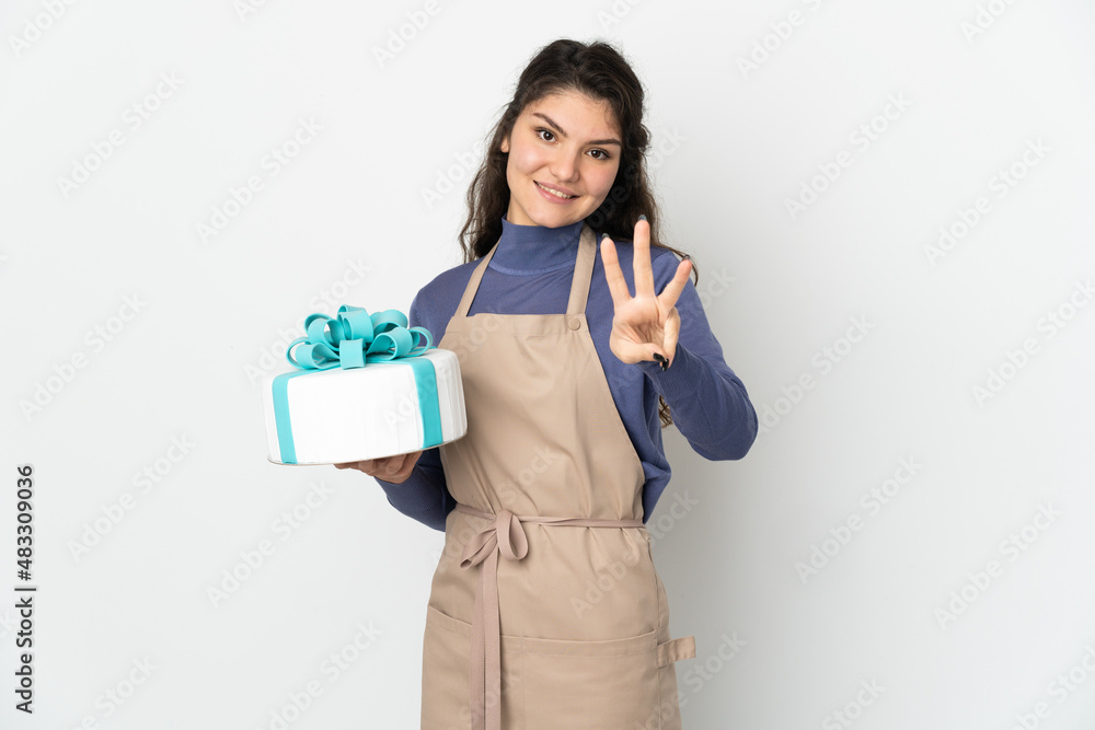 Pastry Russian chef holding a big cake isolated on white background happy and counting three with fingers Pastry Russian chef holding a big cake isolated on white background happy and counting three with fingers