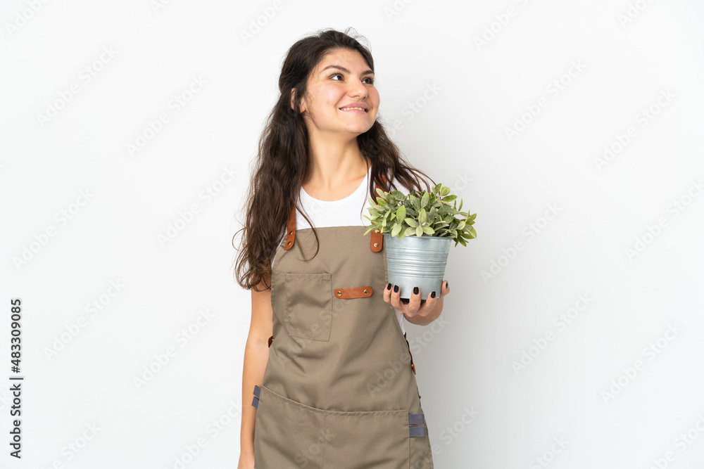Young Russian gardener girl holding a plant isolated thinking an idea while looking up Young Russian gardener girl holding a plant isolated thinking an idea while looking up
