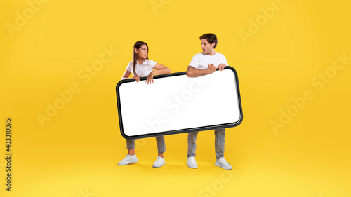 Couple holding big white empty smartphone screen photo