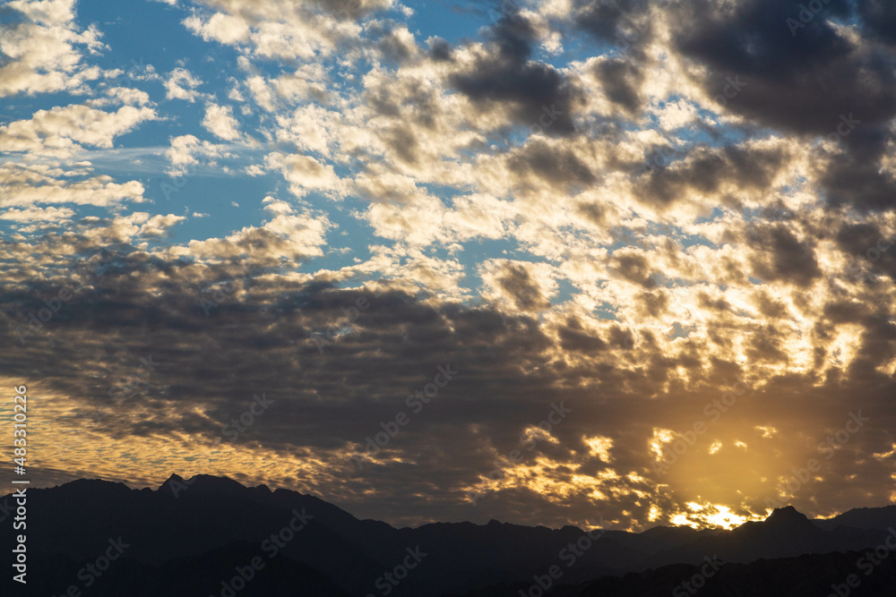 Obraz premium Dramatic scenes with cloudy sky and dark silhouette of Sinai mountains and orange sunset. Dahab, Sinai peninsula, Egypt