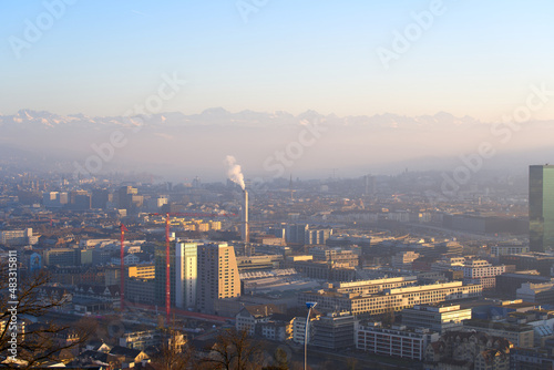 Aerial view over City of Zürich with the Swiss Alps and hazy sky in the background on a sunny winter afternoon. Photo taken January 26th, 2022, Zurich, Switzerland.
