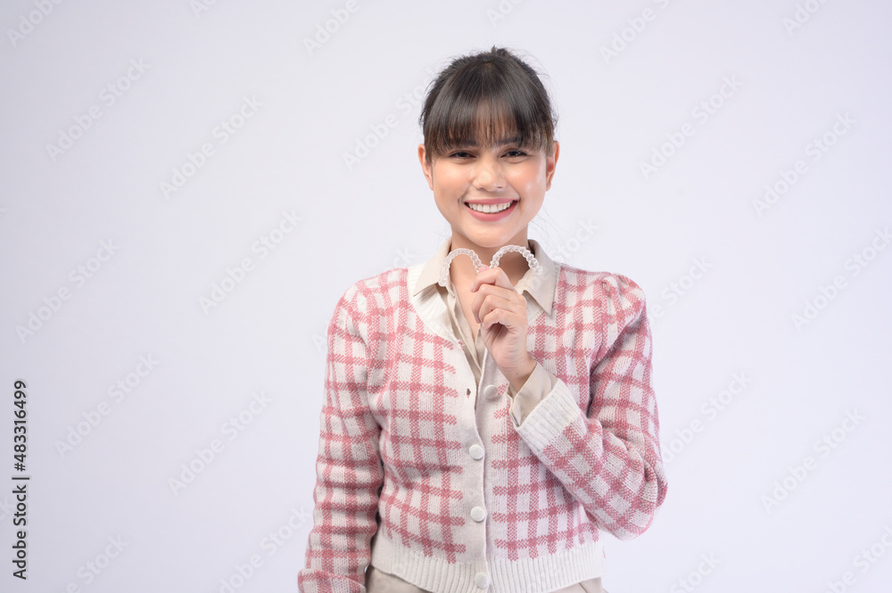 Young smiling woman holding invisalign braces over white background studio, dental healthcare and Orthodontic concept. Young smiling woman holding invisalign braces over white background studio, dental healthcare and Orthodontic concept.