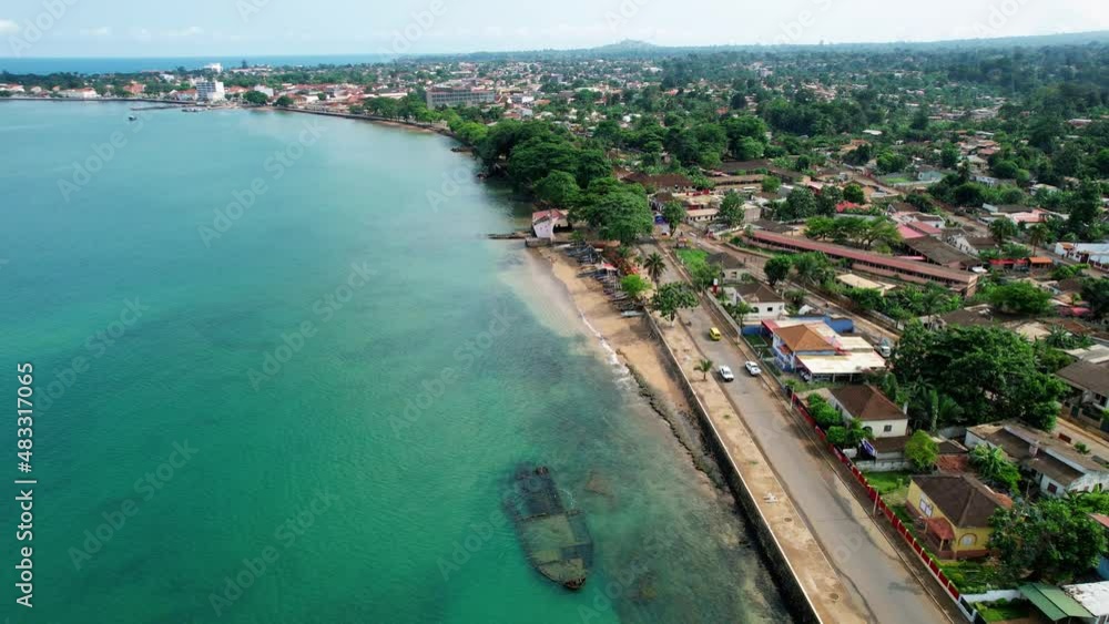 Aerial view of a shipwreck and cars on the coast of Sao Tome city, sunny Africa - circling, drone shot Aerial view of a shipwreck and cars on the coast of Sao Tome city, sunny Africa - circling, drone shot