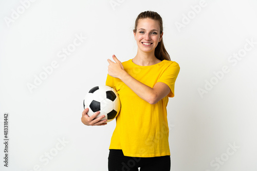 Young caucasian woman isolated on white background with soccer ball and pointing to the lateral © luismolinero
