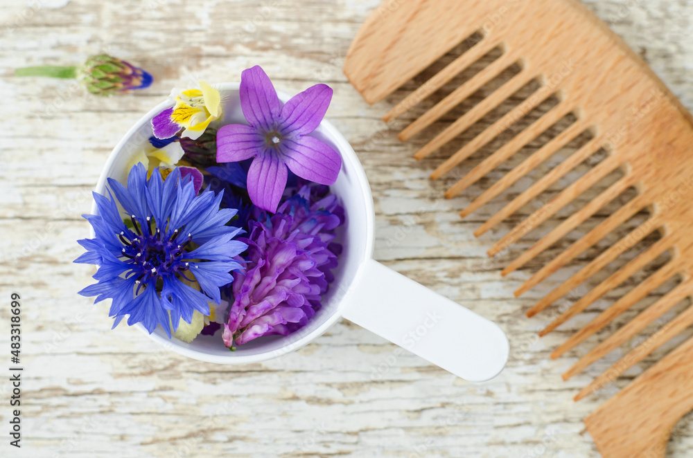 Plastic scoop with various field flowers and hairbrush. Ingredients of natural cosmetic. Organic hair care, homemade beauty treatment and spa concept. Plastic scoop with various field flowers and hairbrush. Ingredients of natural cosmetic. Organic hair care, homemade beauty treatment and spa concept.