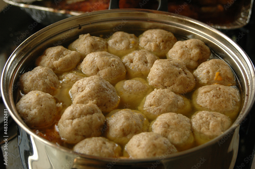 Traditional Jewish holiday meal of chicken soup with matzah balls floating on the surface of a large pot. Traditional Jewish holiday meal of chicken soup with matzah balls floating on the surface of a large pot.