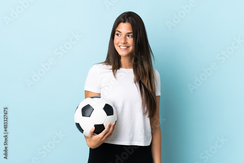 Young football player brazilian girl isolated on blue background looking to the side and smiling © luismolinero