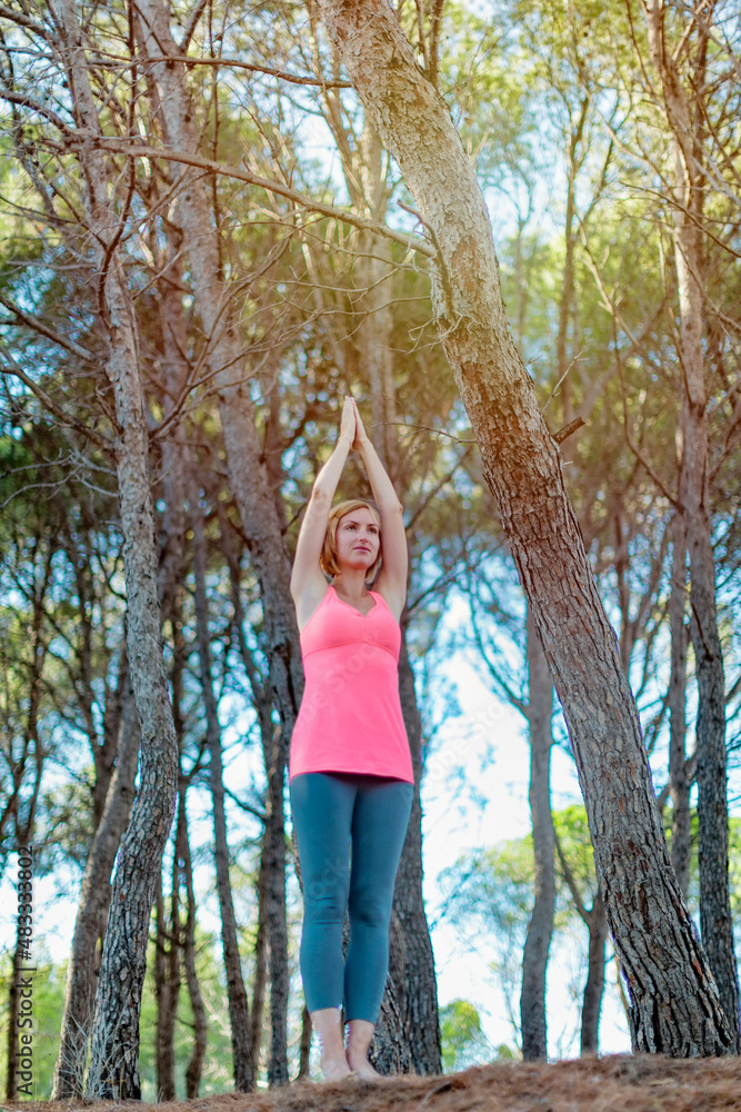 Happy young woman practicing yoga with hands raised up into the woods outdoors. Upward Salute pose Happy young woman practicing yoga with hands raised up into the woods outdoors. Upward Salute pose