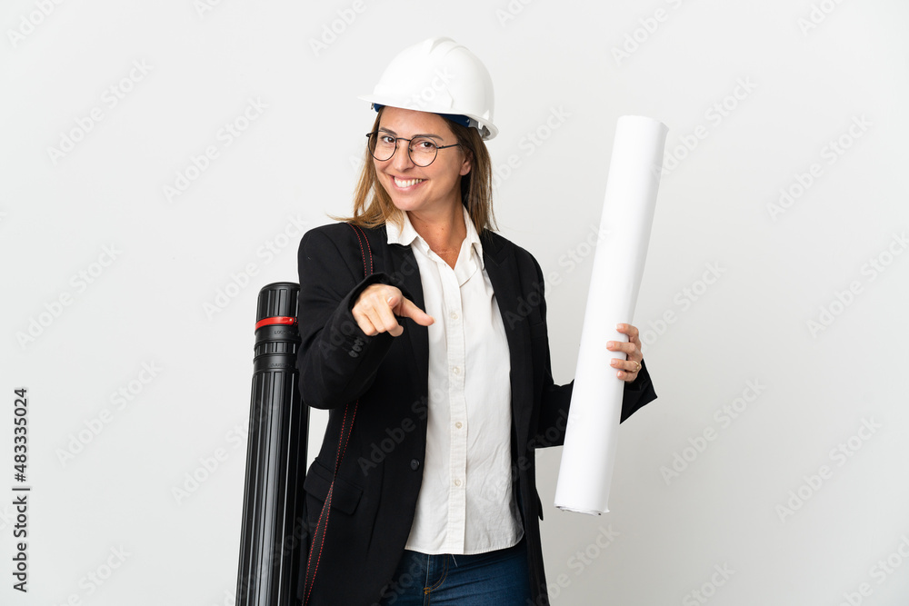 Middle age architect woman with helmet and holding blueprints over isolated background pointing front with happy expression Middle age architect woman with helmet and holding blueprints over isolated background pointing front with happy expression