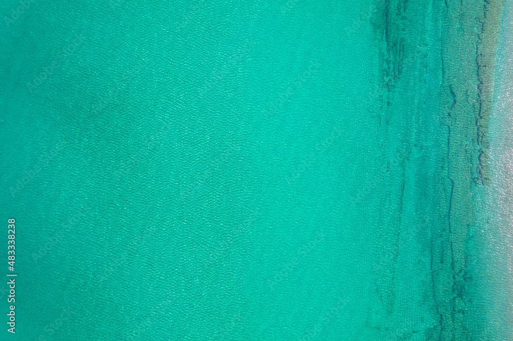 Background, texture of relaxing, calm turquoise, transparent sea water with stones, slabs, lump, coral. Summer vacation. Blue ocean lagoon. Drone, copter top view.
