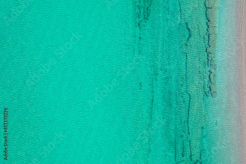 Background, texture of relaxing, calm turquoise, transparent sea water with stones, slabs, lump, coral. Summer vacation. Blue ocean lagoon. Drone, copter top view.