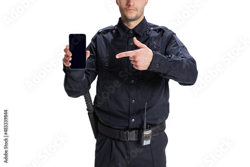 Portrait of young man, policeman officer wearing black uniform using phone isolated on white background. Concept of job, caree, law and order. photo