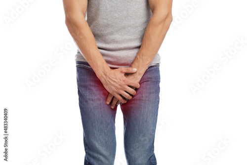 Unrecognizable young european guy suffer from crotch pain, presses hands, highlighted in red © Prostock-studio