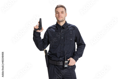 Half-length portrait of young male policeman officer wearing black uniform posing with gun isolated on white background. Concept of job, caree, law and order.