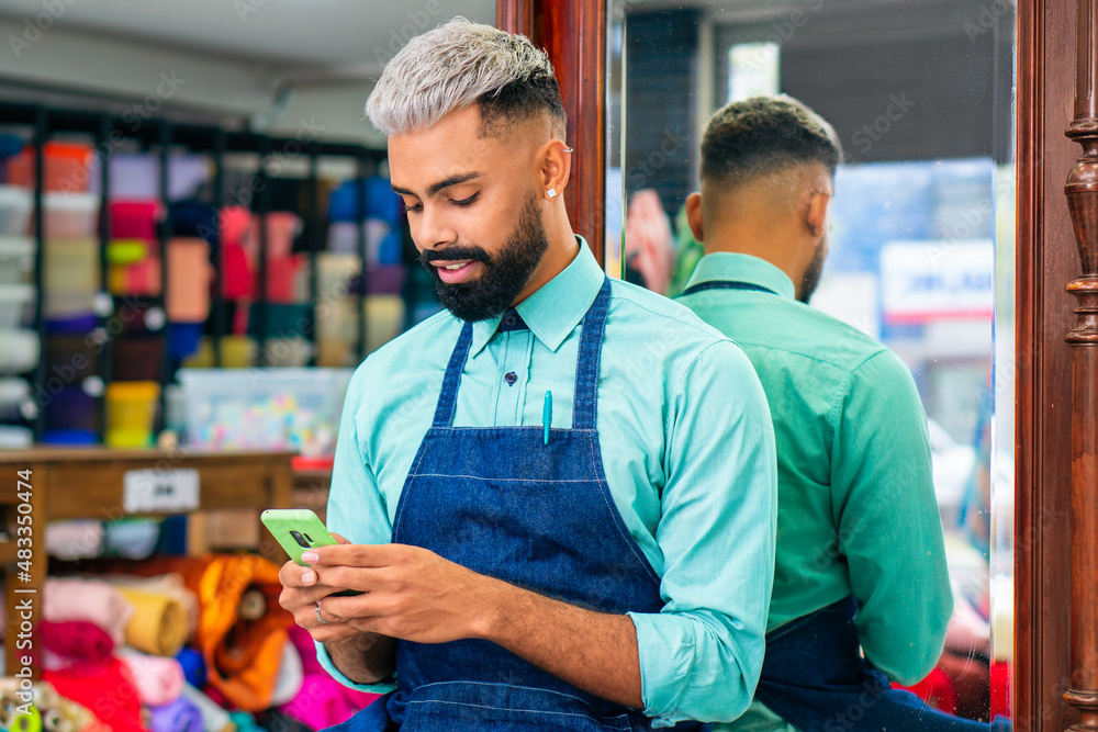 distracted store seller using mobile phone to check messages at fabric ...