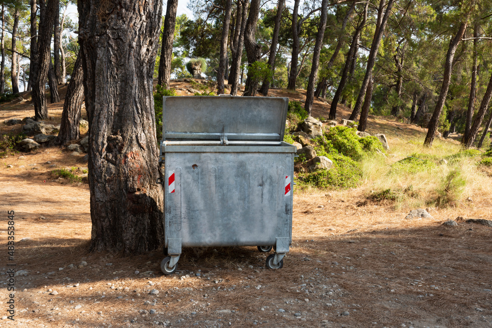 Old metal garbage container on the forest, trash dumpster. Dirty refuse bin. Garbage containers on the park. Recycling industry. Ecology, beautiful natural environment. Recycle bin front view. Old metal garbage container on the forest, trash dumpster. Dirty refuse bin. Garbage containers on the park. Recycling industry. Ecology, beautiful natural environment. Recycle bin front view.