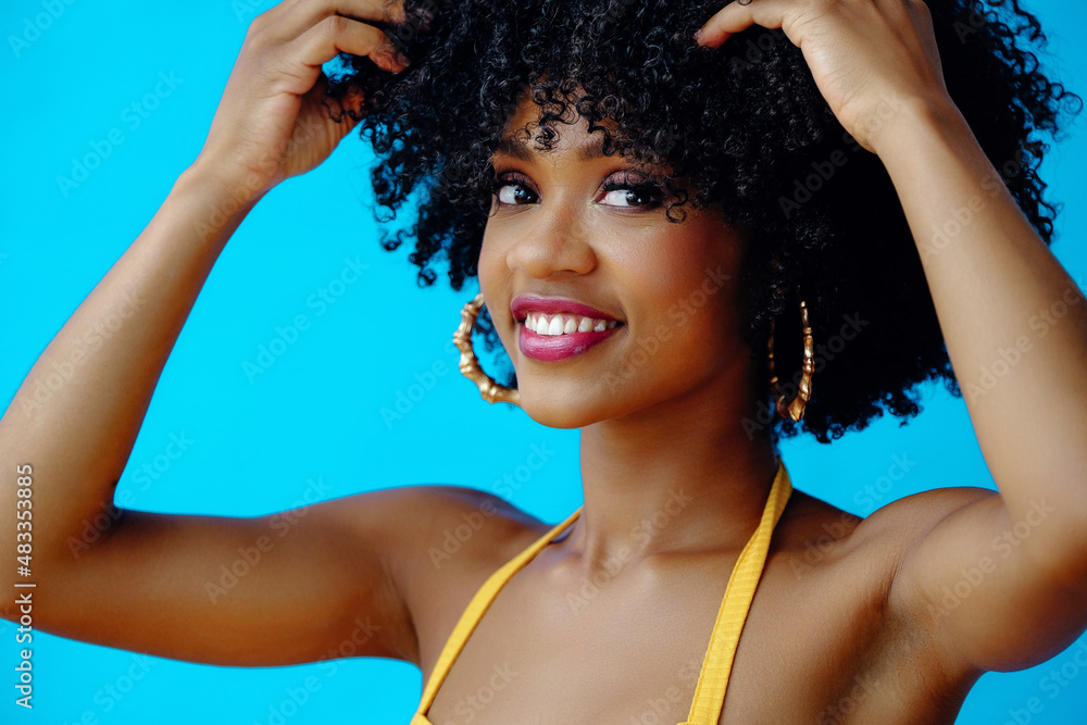 young beautiful woman with hands on curly hair looking at the camera posing in studio