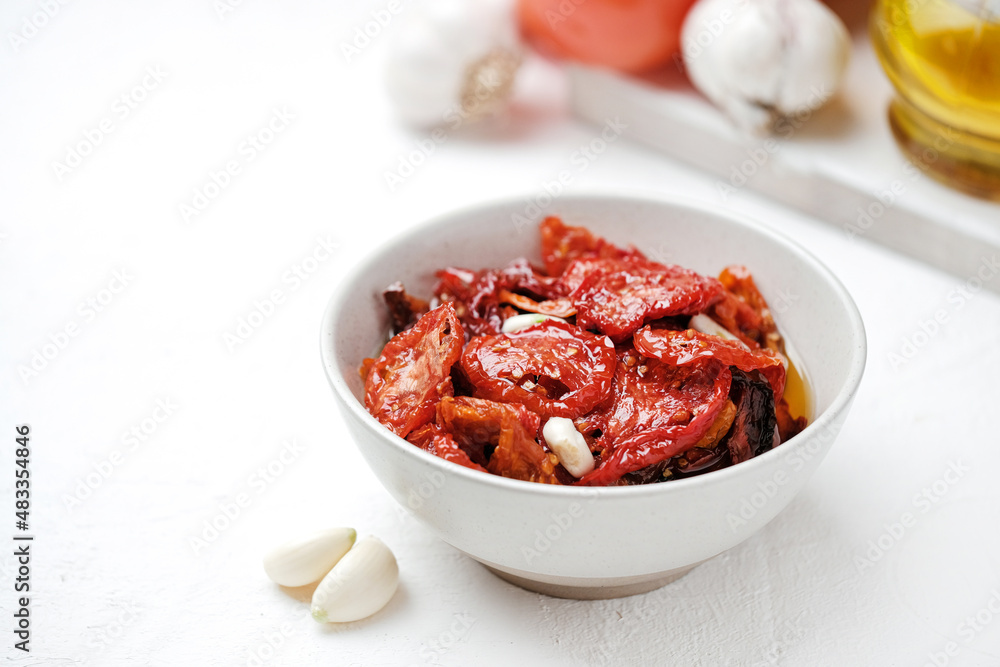 Sun dried tomatoes on white bowl, white wooden background. Dried tomatoes with olive oil, salt, herbs and garlic recipe. Top view, copyspace. Sun dried tomatoes on white bowl, white wooden background. Dried tomatoes with olive oil, salt, herbs and garlic recipe. Top view, copyspace.