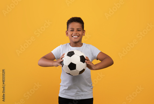 Cheerful black school boy holding soccer ball photo