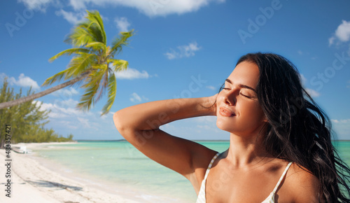 people, summer and swimwear concept - happy beautiful young woman in bikini swimsuit over tropical beach background in french polynesia