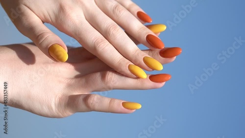 Hands of a young woman with a bright beautiful manicure against the sky