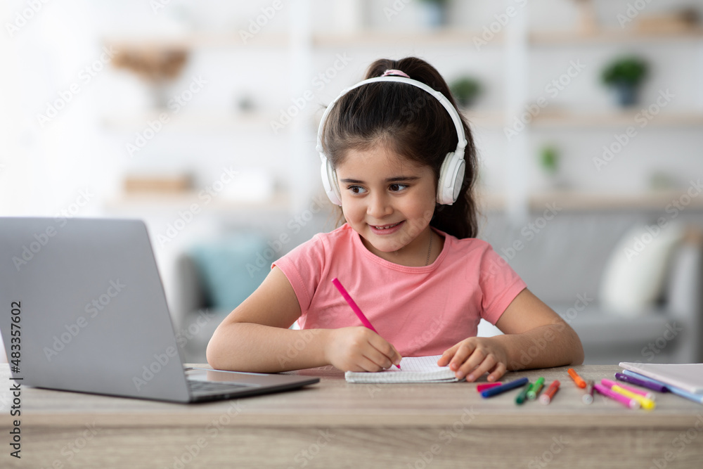 Distance Education. Arab Female Child Wearing Headphones Study With Laptop At Home Distance Education. Arab Female Child Wearing Headphones Study With Laptop At Home