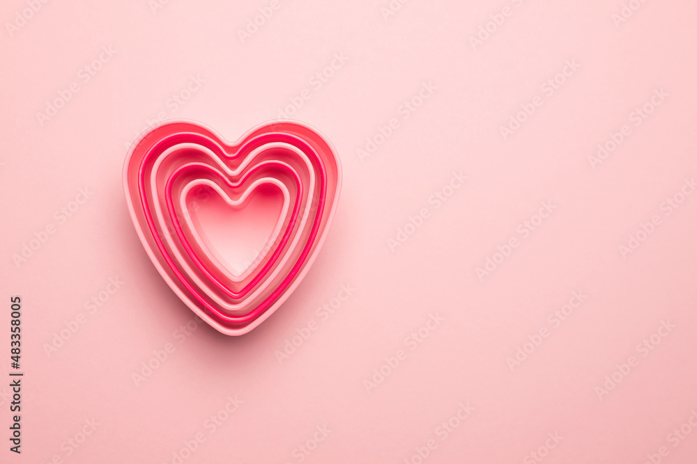 Сolorful cutters cookies in heart shape on pastel pink background. Concept Valentine's card. Top view Copy space for text.
