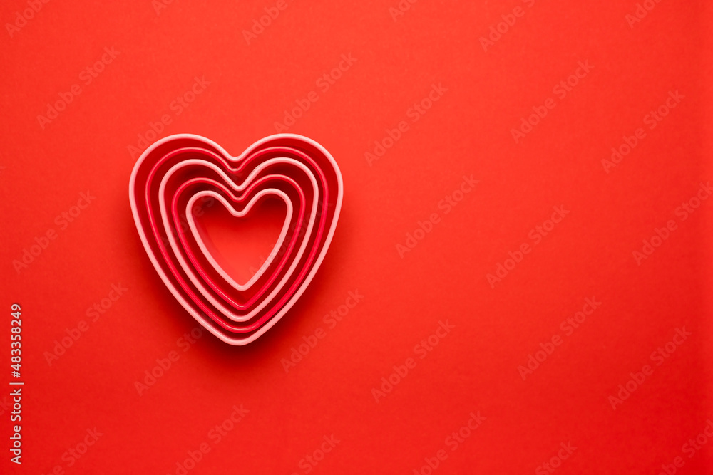 Сolorful cutters cookies in heart shape on red background. Concept Valentine's card. Top view Copy space for text.