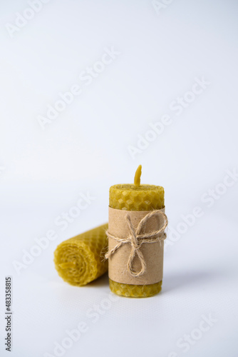two wax candles wrapped in kraft paper and tied with twine on a white background. natural beeswax. handmade candles