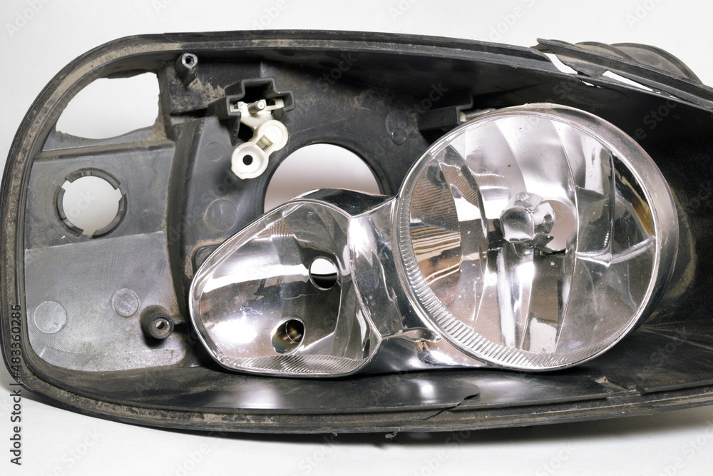 parts of disassembled headlight. cracked black plastic housing and