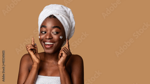 Beautiful young black woman posing with cream on cheek