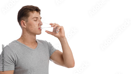 Handsome calm muscular young caucasian guy drinking water from glass, isolated on white background