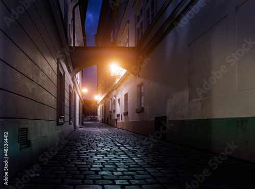 Prague night street with cobblestone arch and lights