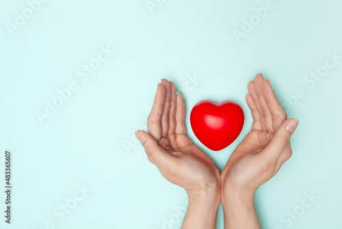 Health  medicine and charity concept - close up of female hands with small red heart.