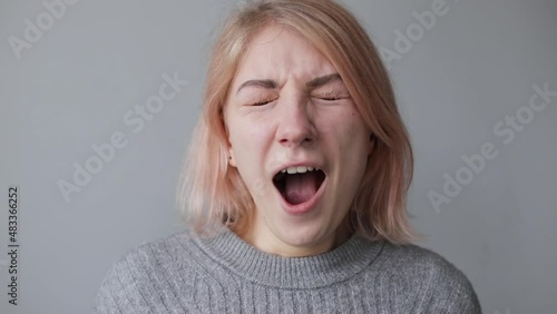 Portrait of a young tired woman looking at the camera and yawning photo