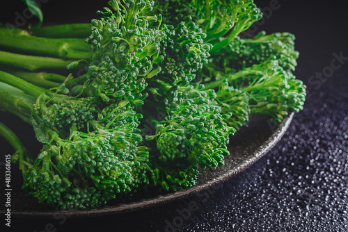 Fresh bimi vegetable on a dark table. Raw baby broccoli. Closeup of raw baby broccoli with water droplets.