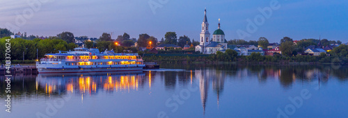 View to St. Catherine monastery with cruise ship on Volga river in summer evening. Beautiful night Russian panoramic cityscape with cruise liner on water. Travel blog concept, banner. Tver, Russia