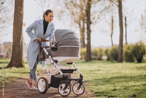 Young asian woman mother, walking with baby stroller in park photo