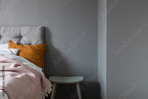 Bed with gray headboard by a dark grey wall photo