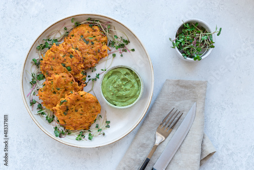 Fototapete Vegan sweet potato fritters with creamy guacamole and microgreens on ceramic plate
