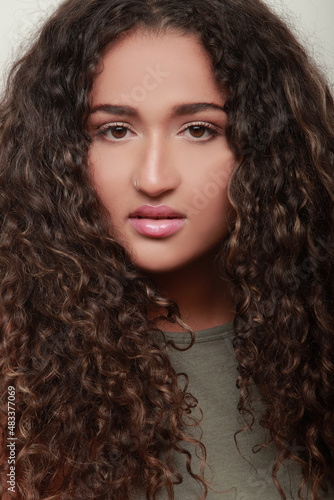 portrait of beautiful latina girl with long curly hair looking at camera