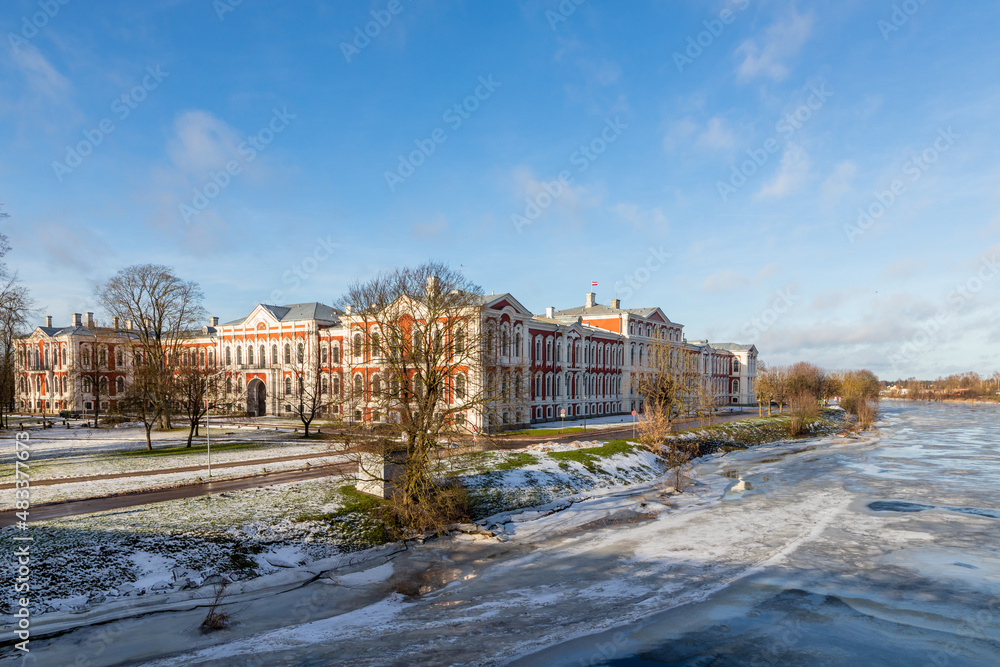 View to Jelgava Palace or historically Mitau Place built in the 18th century and ice covered river Lielupe from traffic bridge. Baroque-style university, museum, residence in Jelgava.