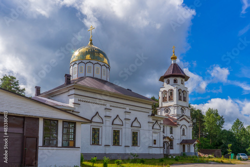 Church to St. Grand Prince Alexander Nevsky in Pudozh after restoration. Orthodox temple and bell tower against northern pine forest and blue sky in summer sunny day. Karelia  Russia
