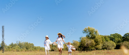 Sisters walk across the field, holding hands. Time with family. Cheerful picnic in the park