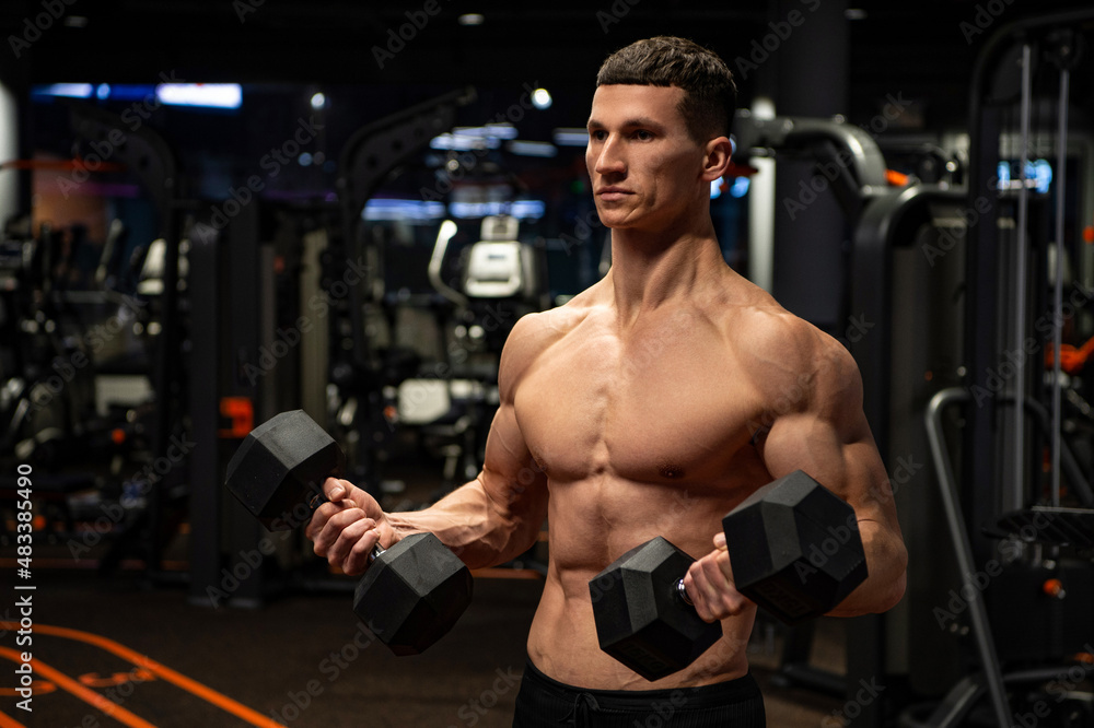 Shirtless man doing tricep curls with dumbbells in gym, triceps workout