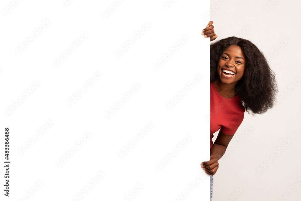Joyful Young Black Lady Standing Behind Big White Advertisement Board Joyful Young Black Lady Standing Behind Big White Advertisement Board