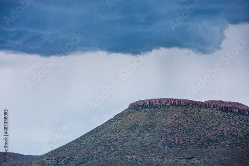 I hilltop in the Karoo in South Africa with an overhanging storm cloud