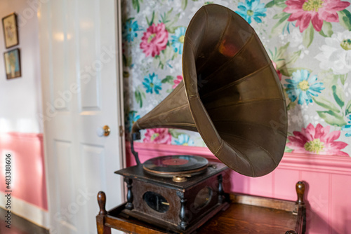 Vintage gramophone on wooden table in house against floral pattern wallpaper, Old gramophone with vinyl on wooden box