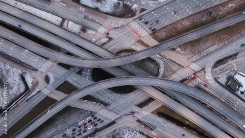 Aerial time lapse traffic jam interchange road, drone shot top down zoom out view roadway intersection in modern city in evening. Timelapse cars driving busy roundabout junction highway in fast motion photo
