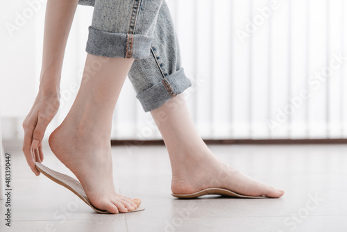 Woman fitting orthopedic insole indoors, close up. Girl holding an insole next to foot at home. Orthopedic insoles. Foot care banner. Flat Feet Correction. Treatment and prevention of foot diseases © mlphoto